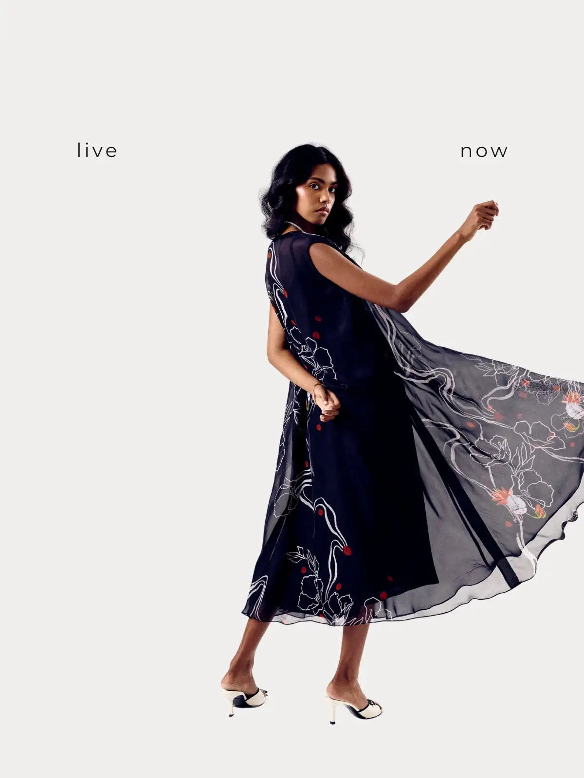 A flowing navy blue dress with delicate floral embroidery in white and red, featuring a sheer overlay that adds movement to its elegant silhouette.