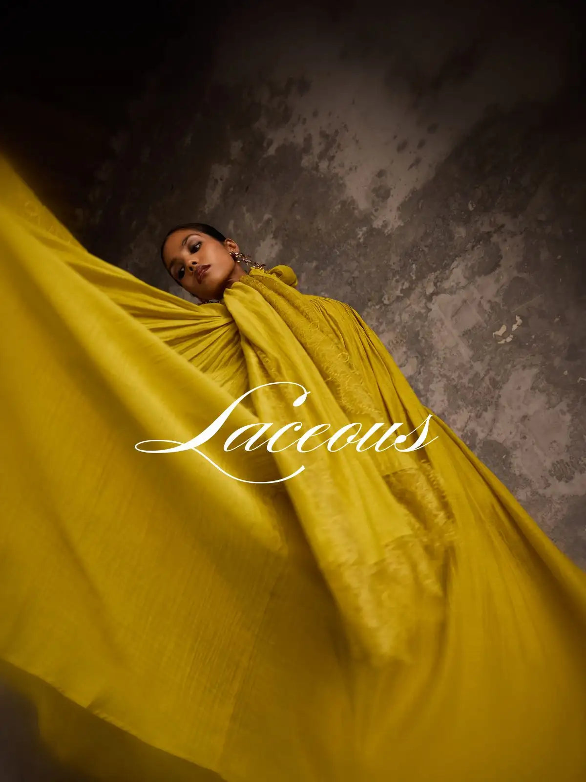 A flowing, vibrant yellow lace gown with intricate detailing and a draped, voluminous silhouette.